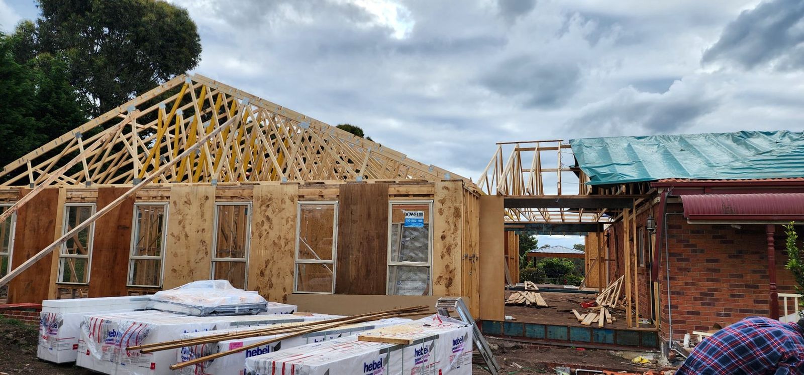 House extension wall framing with windows installed and roof trusses fixed alongside the existing home in Melbourne - Master Framers